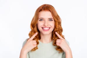 A woman smiling and pointing to her mouth after a smile makeover