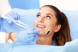 Woman smiling while in dentist chair for year end dental exam