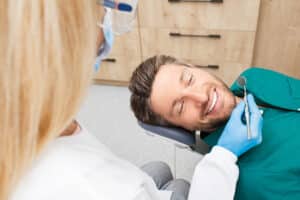 Man smiling while having his teeth professionally cleaned in his dental office