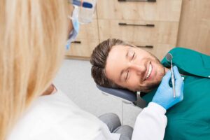 Man smiling while having his teeth professionally cleaned in his dental office