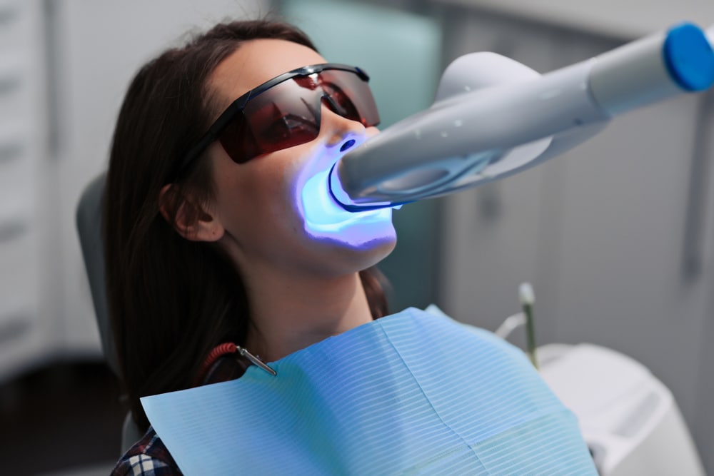 Woman receiving Zoom Whitening treatment for brighter, whiter teeth.