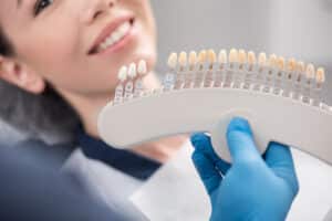 Woman smiling while having her teeth color-matched for her dental veneers