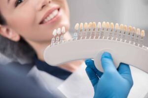 Woman smiling while having her teeth color-matched for her dental veneers