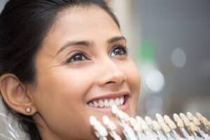 Close up of a smiling woman having her teeth color-matched for her porcelain veneers.