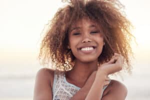 Beautiful young woman showing off a big smile while standing in the sunlight after her smile makeover treatment